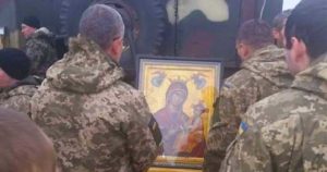 Ukrainian soldiers pray in front of an Icon of the Blessed Virgin Mary